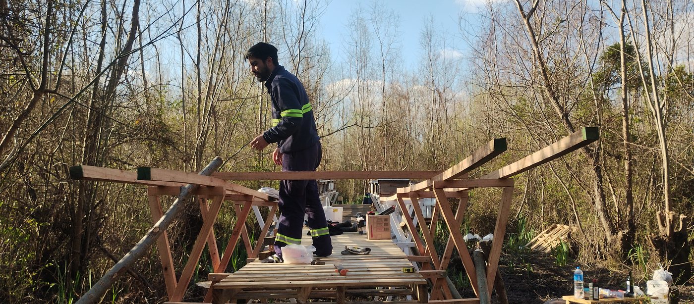 Martín trabajando sobre la pasarela a medio armar, entre el monte