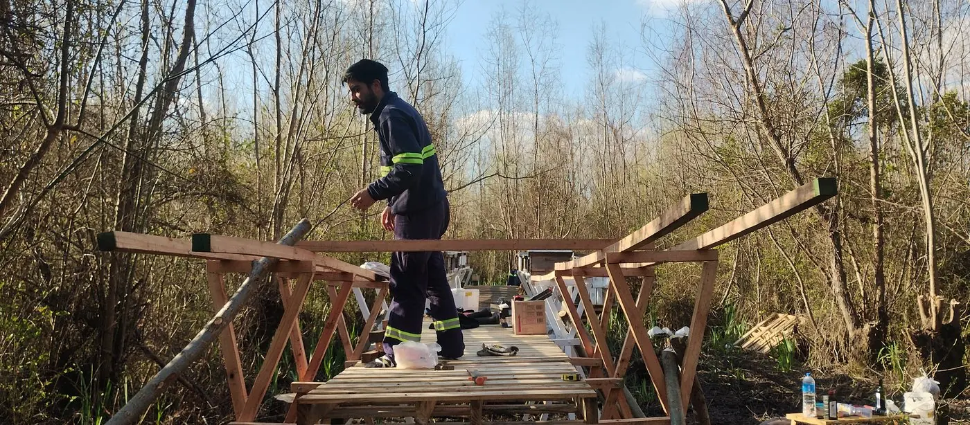 Martín trabajando sobre la pasarela a medio armar, entre el monte